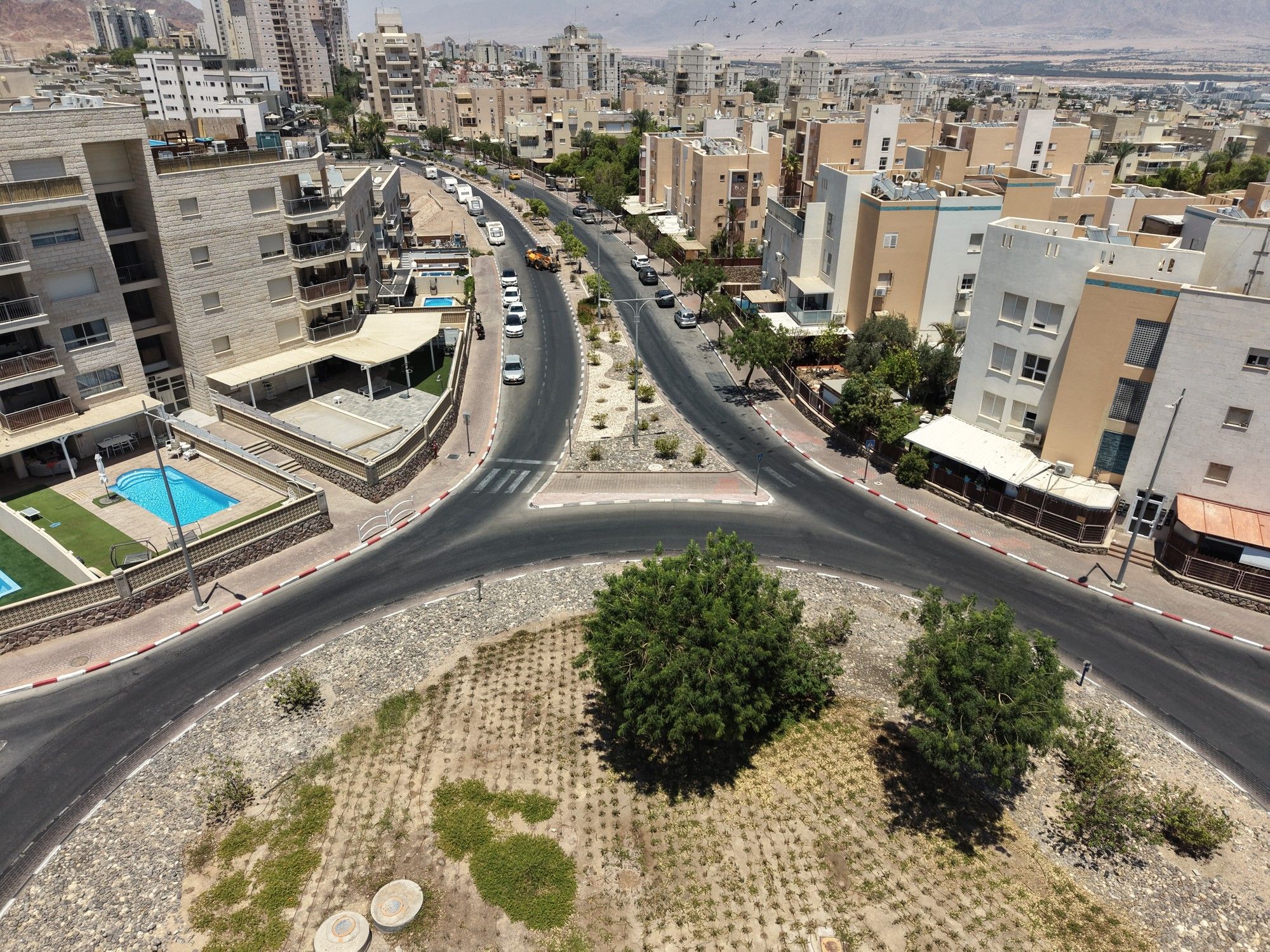 כיכר עם עצים וגינון מדברי, בין בנייני השכונה