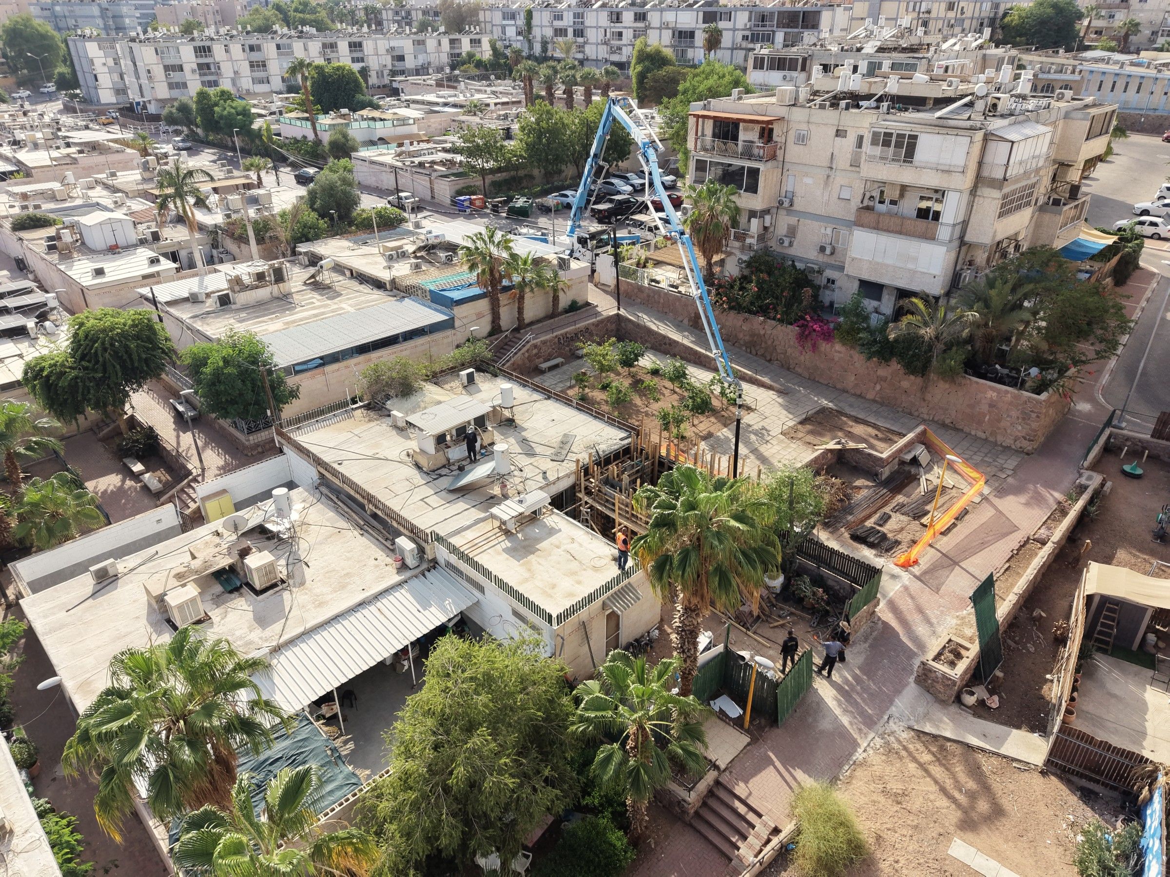 משאבת בטון פרוסה מעל גגות שכונת אופיר אל אתר העבודה שבין הבתים