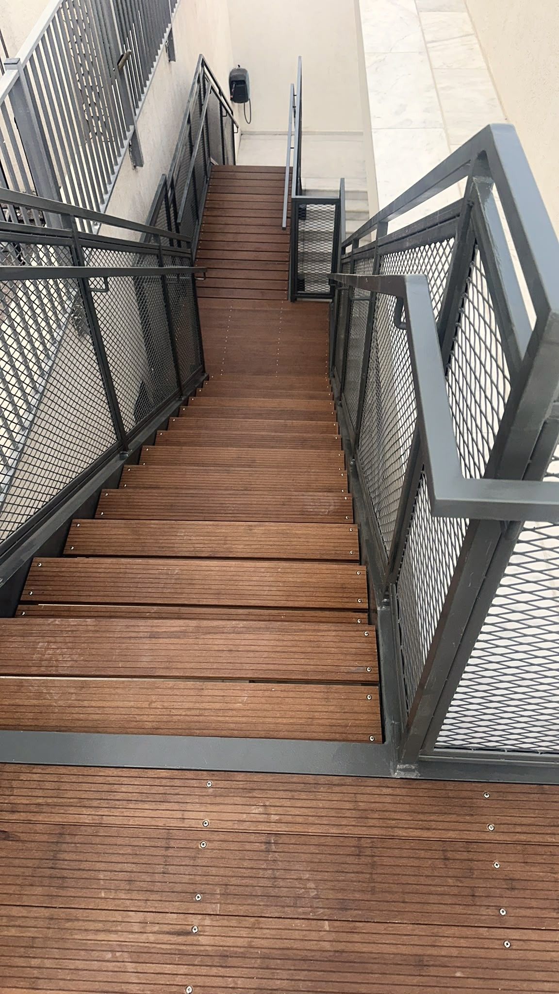 גרם מדרגות פלדה עם שלבי עץ ומעקות רשת, מבט מלמעלה