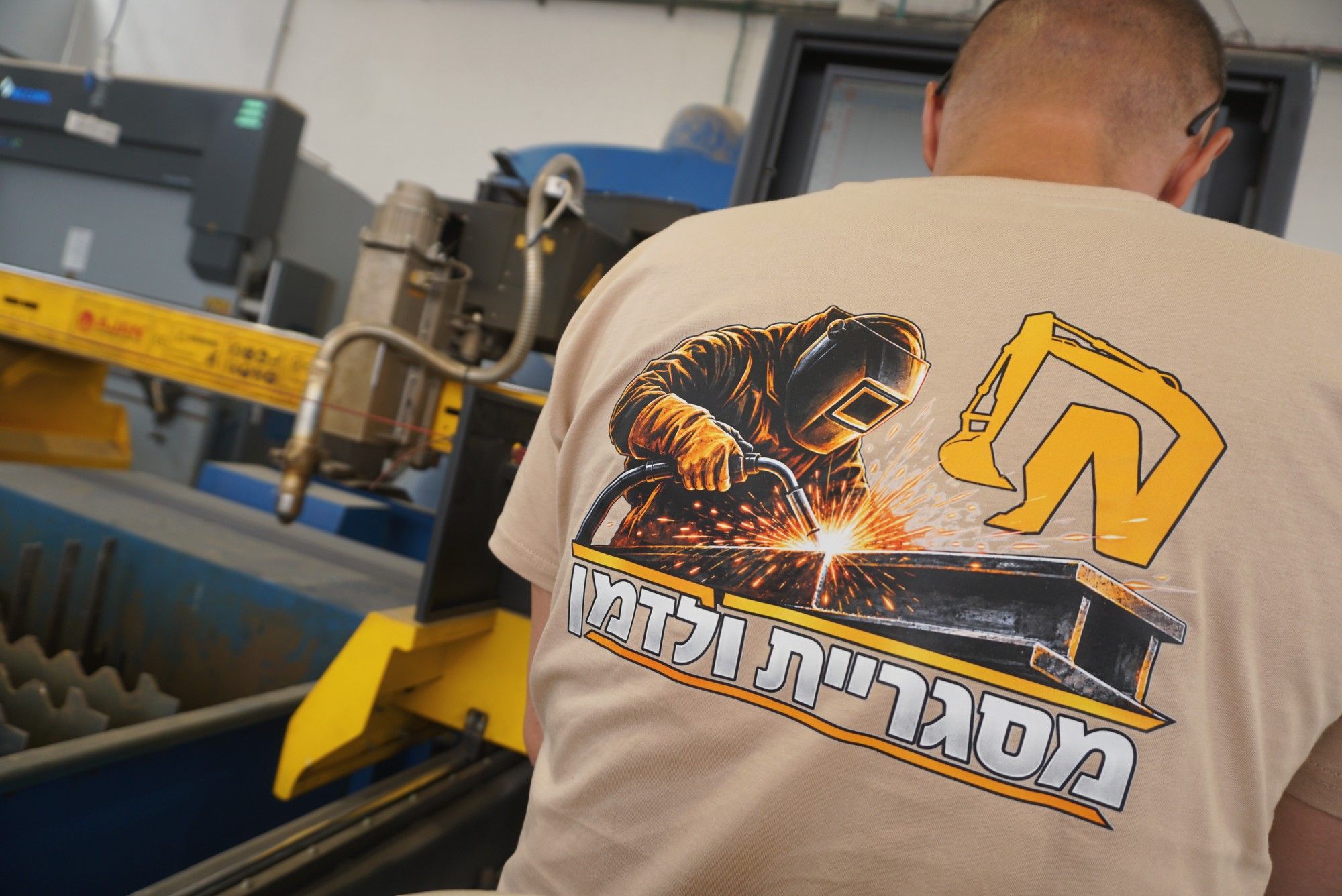 עובד בחולצת מסגריית ולדמן ליד שולחן חיתוך הפלזמה