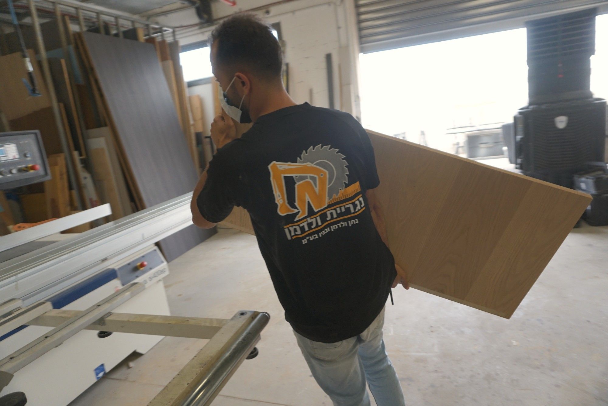נגר בחולצת נגריית ולדמן נושא לוח עץ